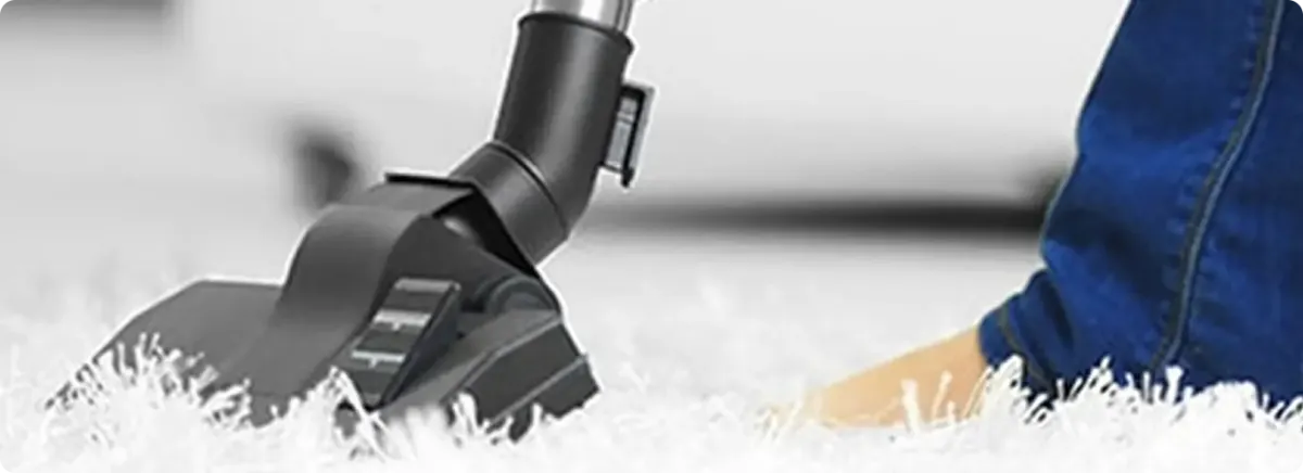 Close-up of a professional vacuuming a white carpet in Central Falls.