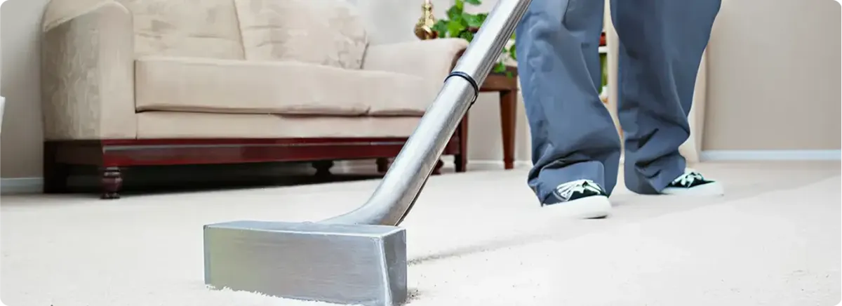 Carpet cleaning technician using a hot-water extraction wand on a light-colored carpet in a living room, Providence, RI.